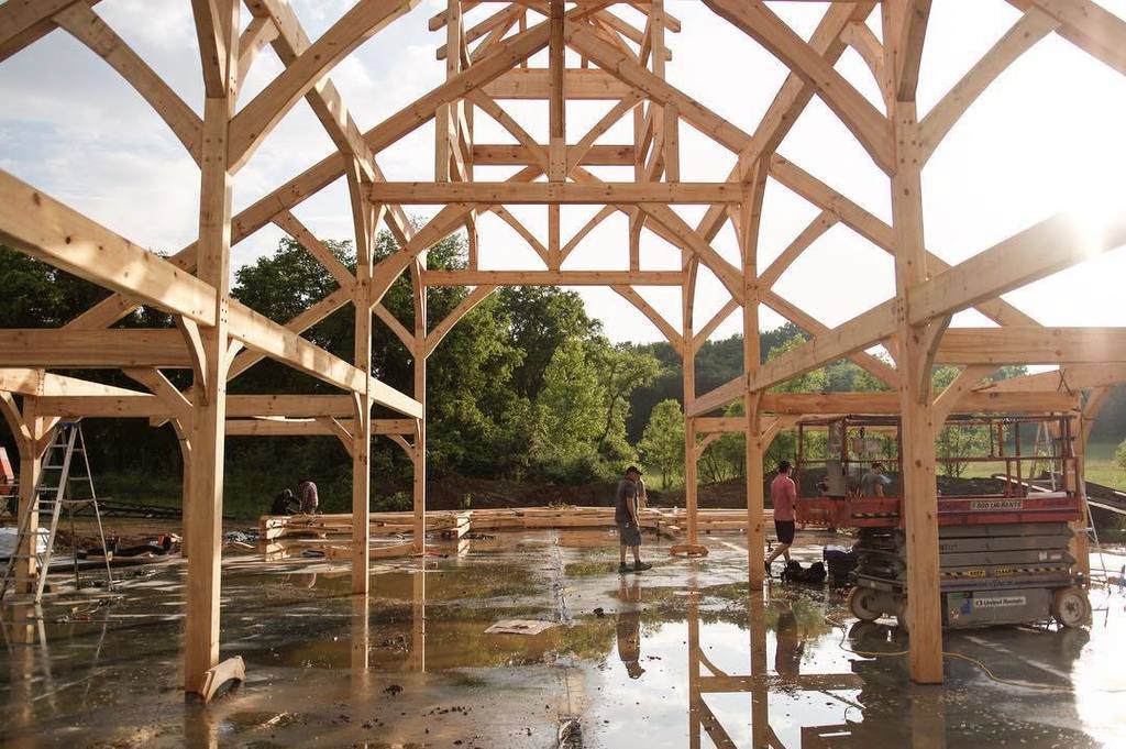 Timber frame bents standing on a wet slab during the raising