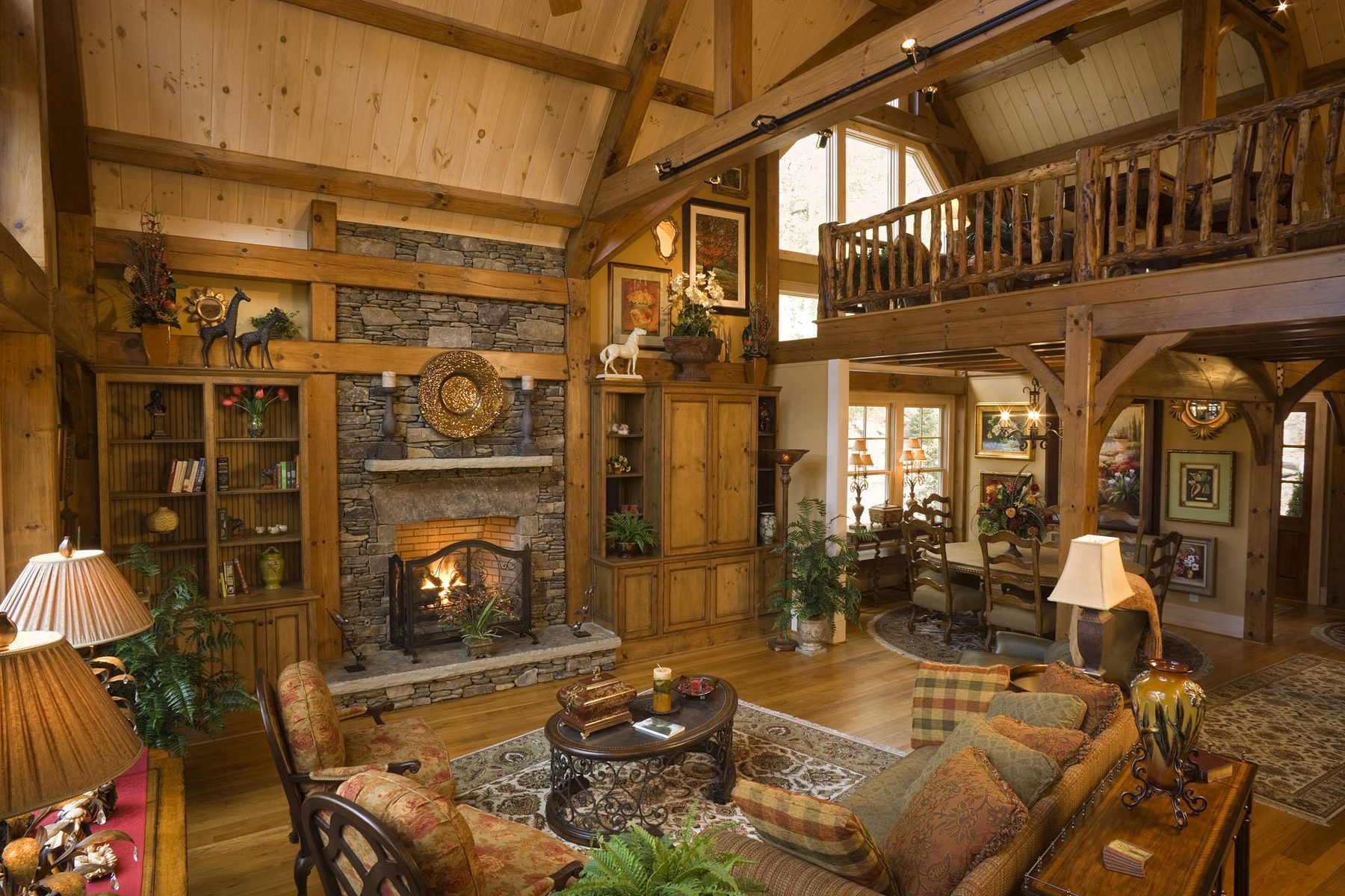 Great room beneath the 27-foot queen-post truss with dry-stack fieldstone hearth and loft rail above