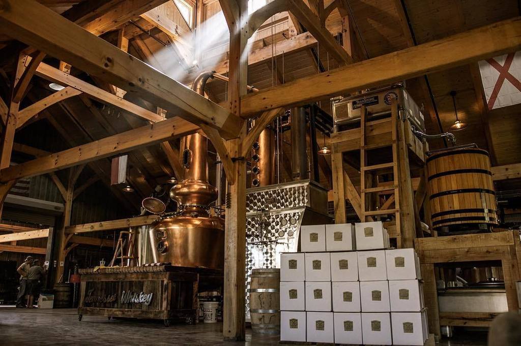 Stillhouse floor with cased whiskey stacked beside the copper still